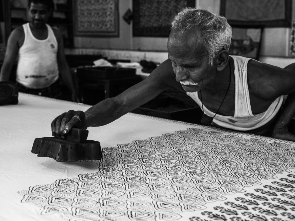 an old man printing patterns with ink on a piece of fabric